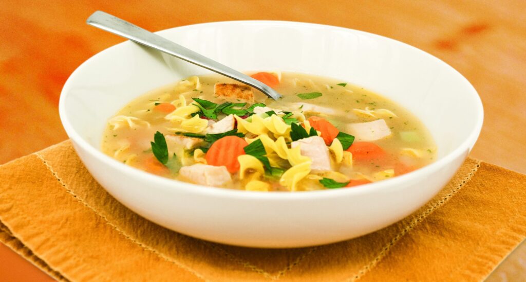 Turkey noodle soup with egg noodles, carrots, and cubed turkey in a light broth