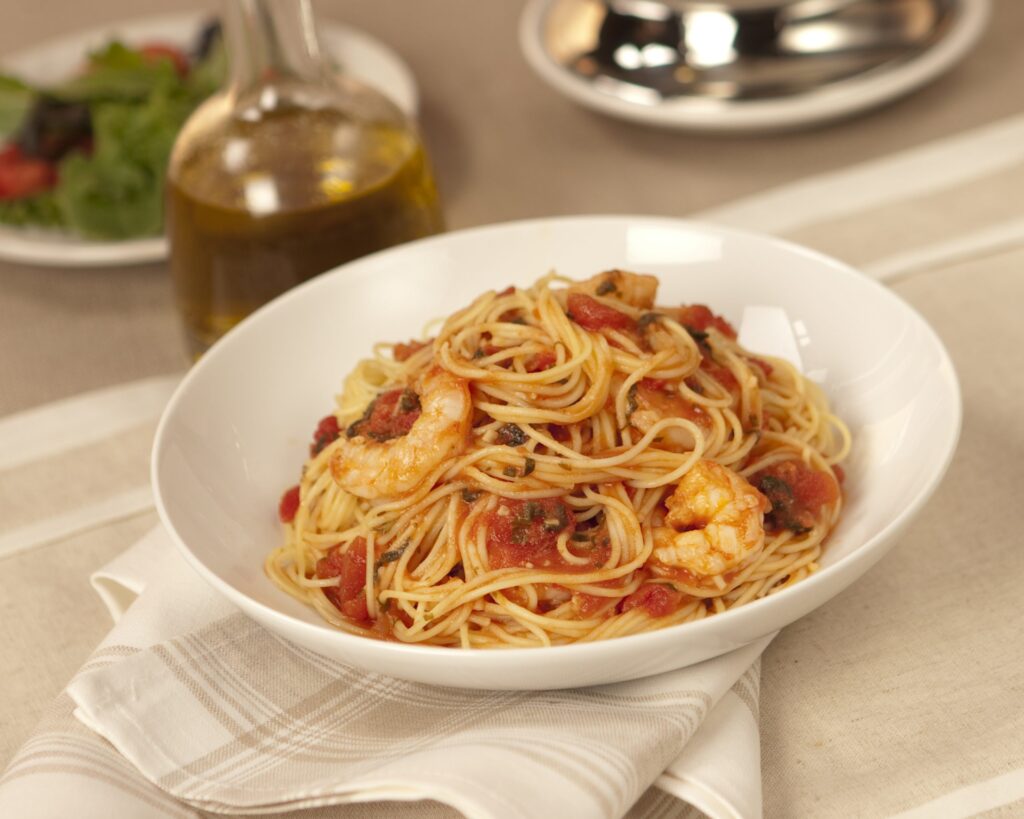 Angel hair pasta with shrimp in a light tomato sauce, topped with fresh basil