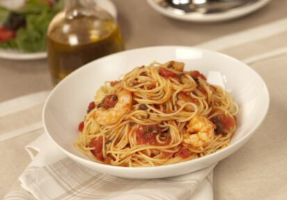 Angel hair pasta with shrimp in a light tomato sauce, topped with fresh basil